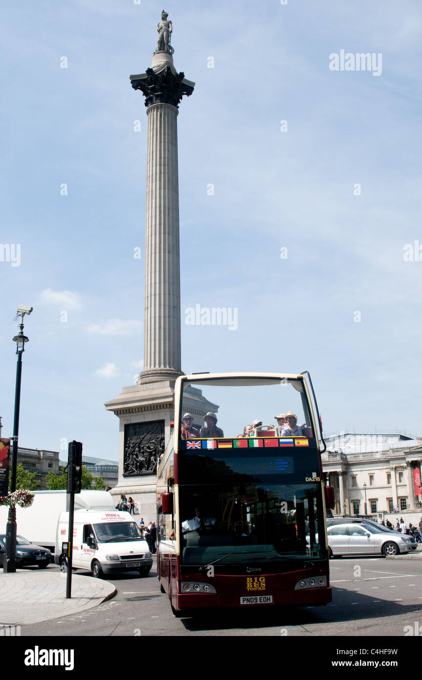 Un open top bus panoramico passa Nelsons Column in Trafalgar Square, Londra Foto Stock