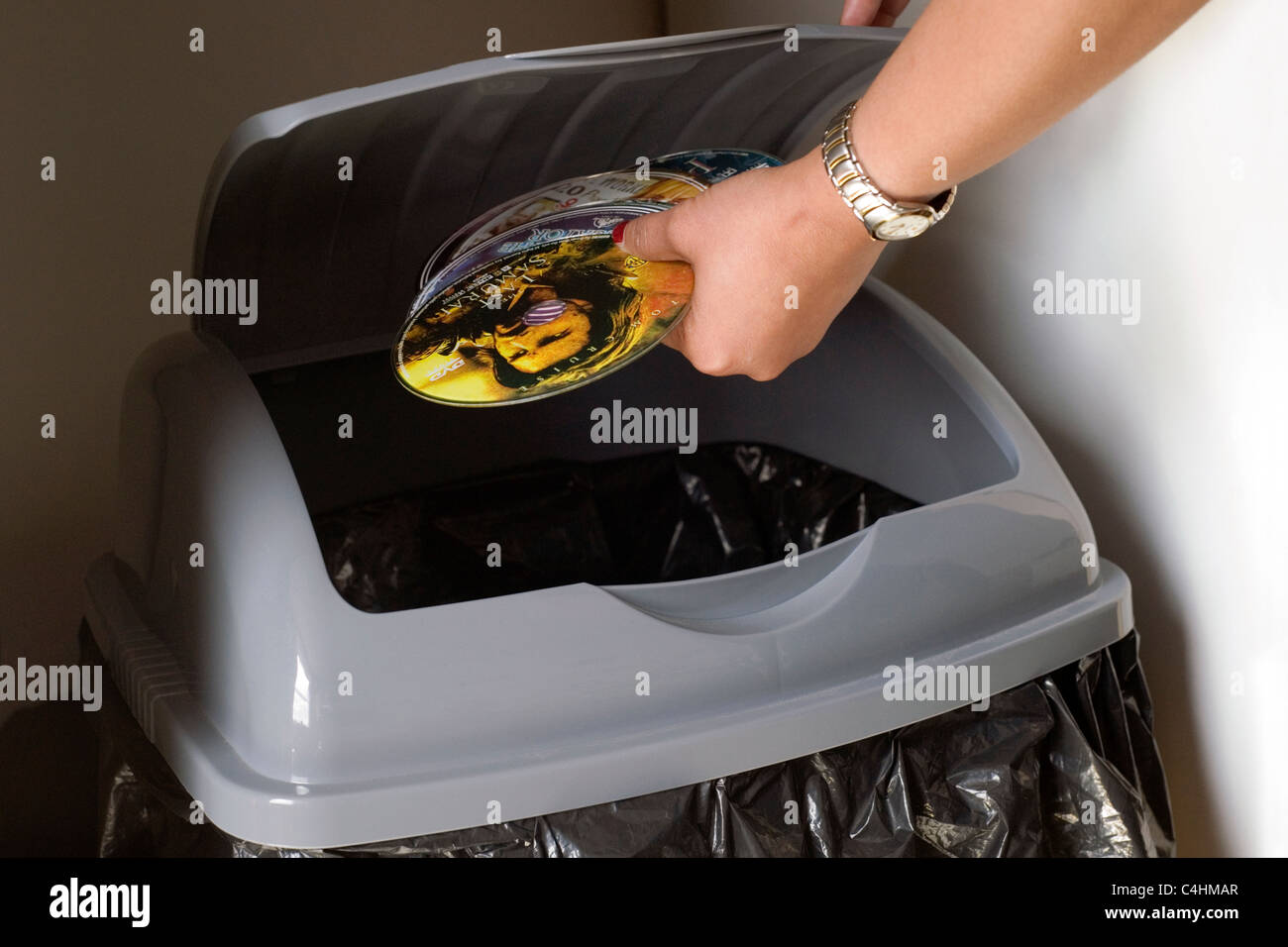 Donna gettando fake movie dischi nel cestino della spazzatura Foto Stock