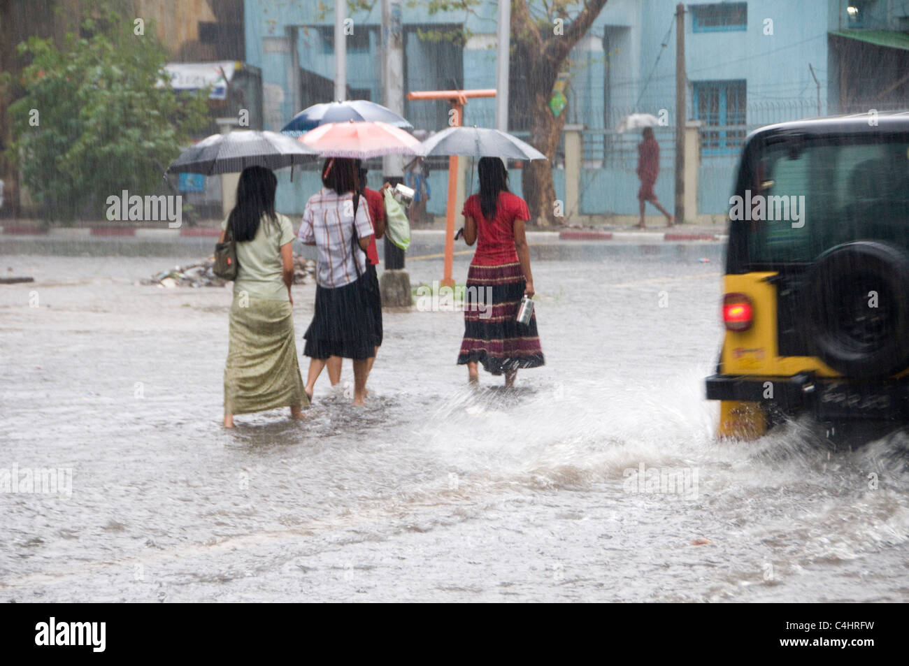 I pedoni camminano con ombrelloni in una strada allagata a causa delle abbondanti precipitazioni nel centro di Yangon in Myanmar Foto Stock
