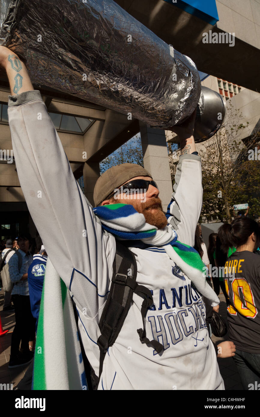 Fiero sostenitore del Vancouver Canucks solleva una simulazione di Stanley Cup sopra la sua testa prima che la loro perdita per il Boston Bruns Foto Stock