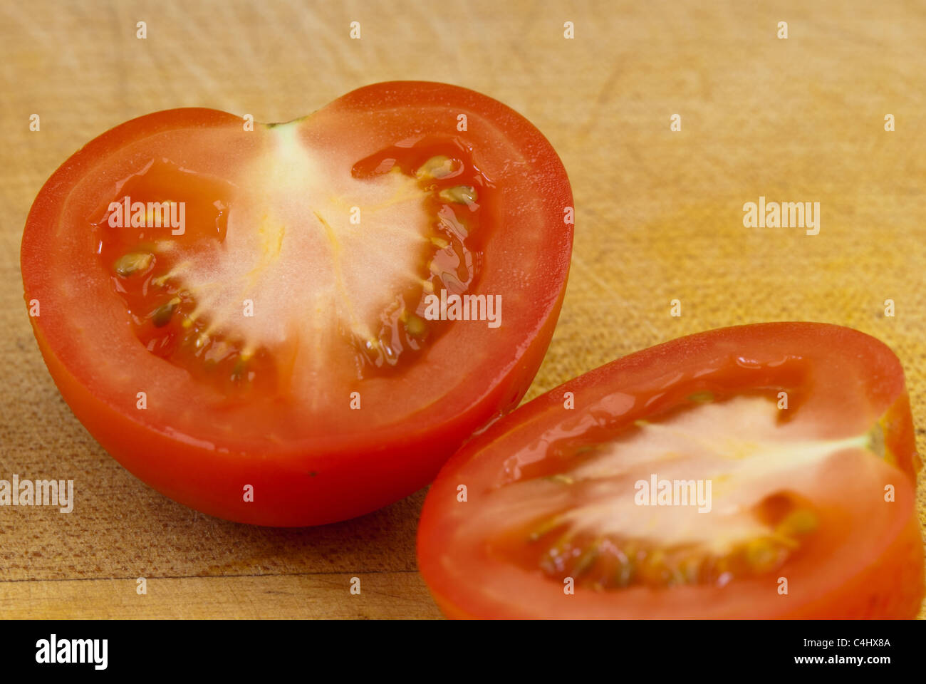 Pomodoro tagliato a metà su una tavola di legno Foto Stock