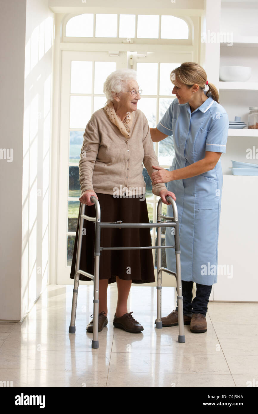 Accompagnatore aiutare anziani donna Senior con telaio a piedi Foto Stock