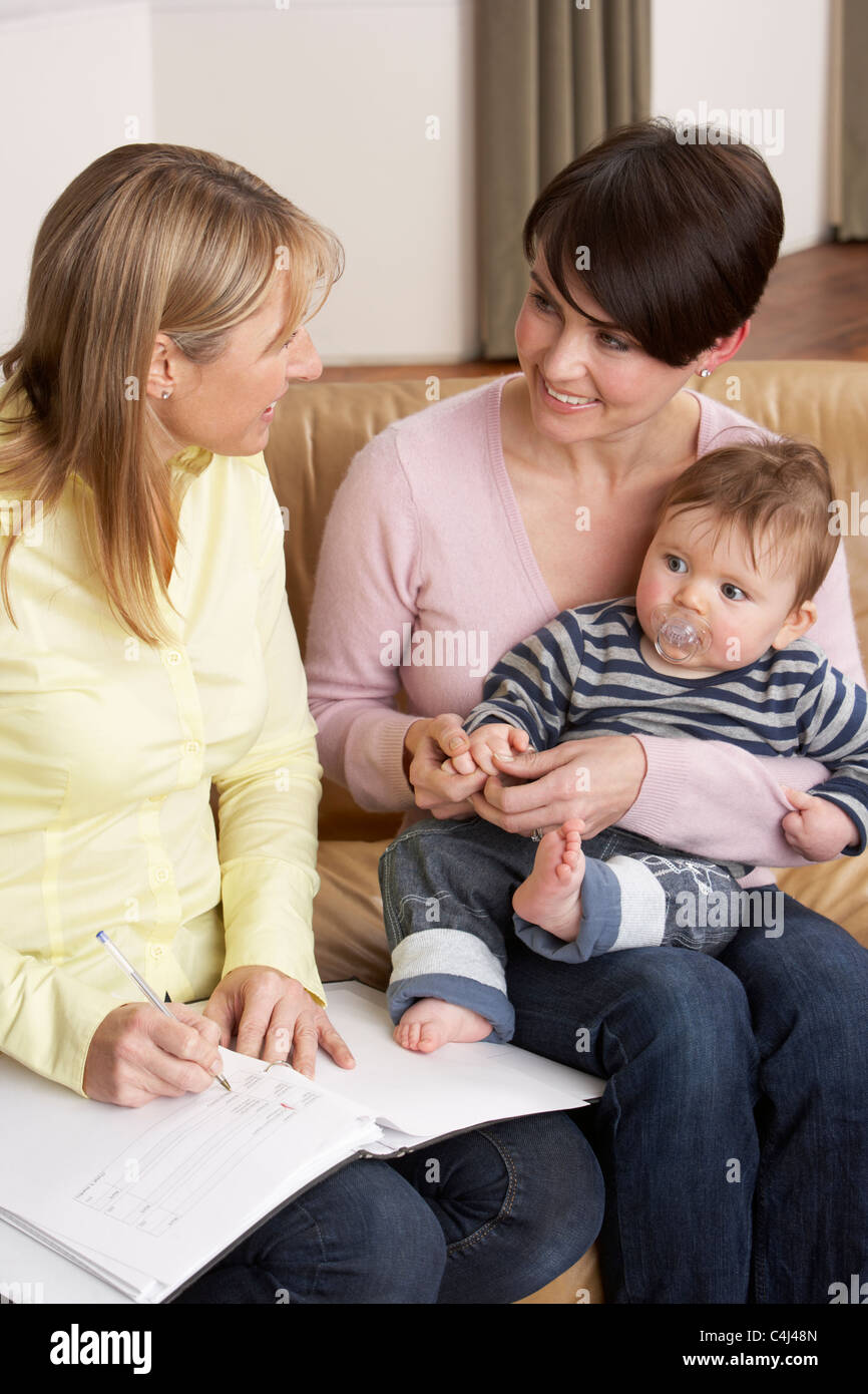 Madre con bambino di parlare con la salute ospite a casa Foto Stock