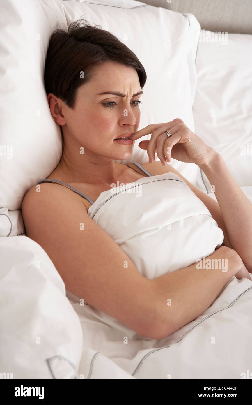 Preoccupato donna recante sveglio a letto Foto Stock