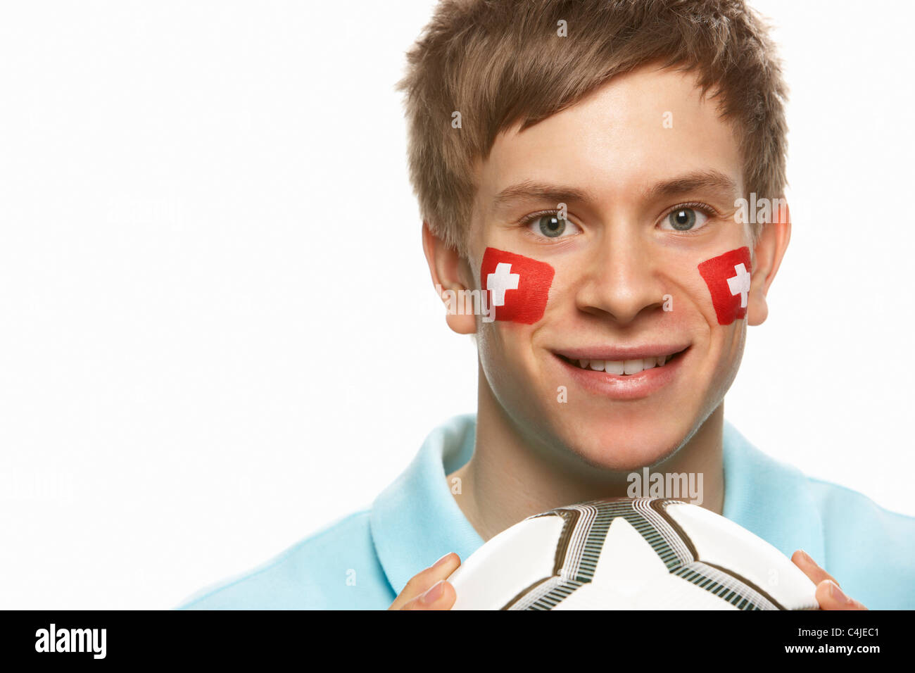 Giovane Maschio appassionato di calcio con la bandiera svizzera dipinto sul volto Foto Stock