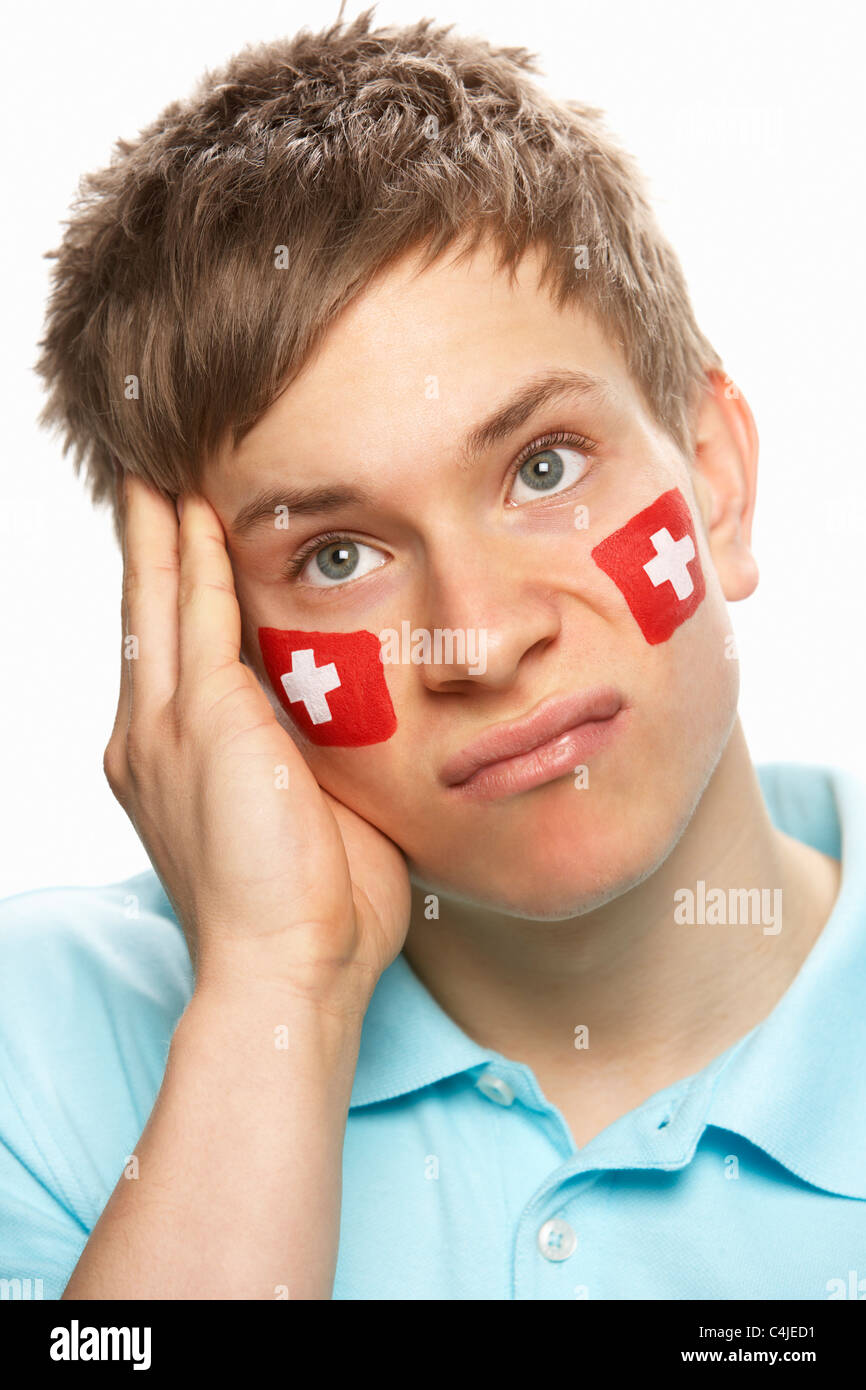 Deluso maschi giovani appassionati di sport con la bandiera svizzera dipinto sul volto Foto Stock