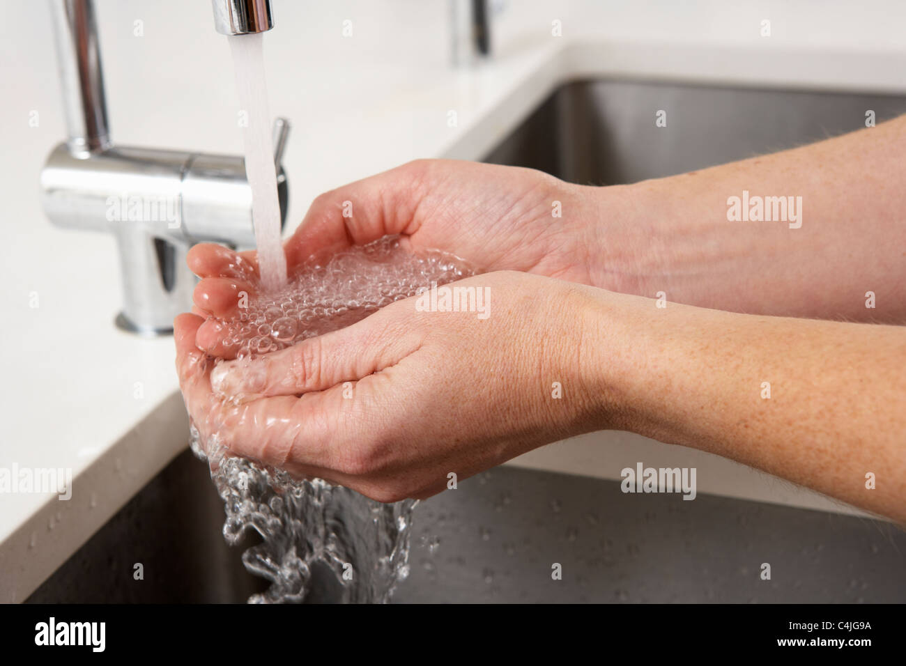 Close up donna lavando le mani al lavello da cucina Foto Stock