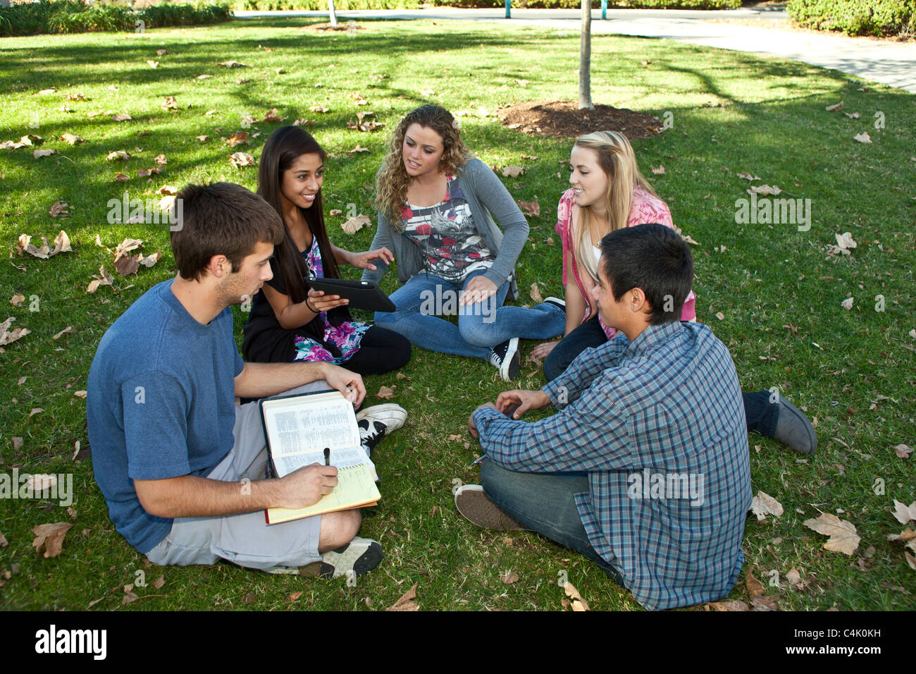 Multi etnico etnicamente diversi gruppo di adolescenti studio discussione insieme utilizzando il telefono cellulare iPhone iPad dispositivi. Signor © Myrleen Pearson Foto Stock