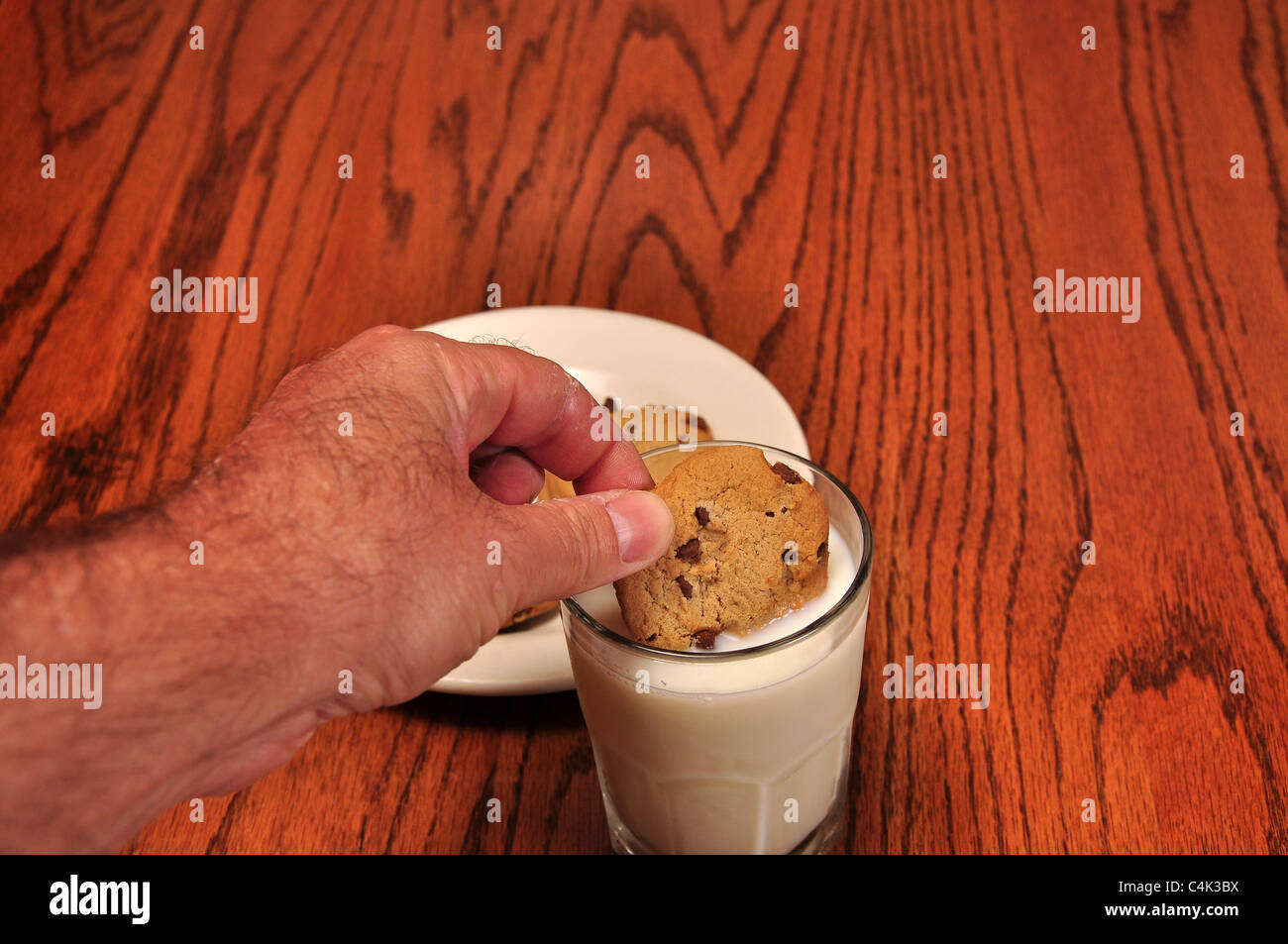 Dunking un cookie in un bicchiere di latte Foto Stock