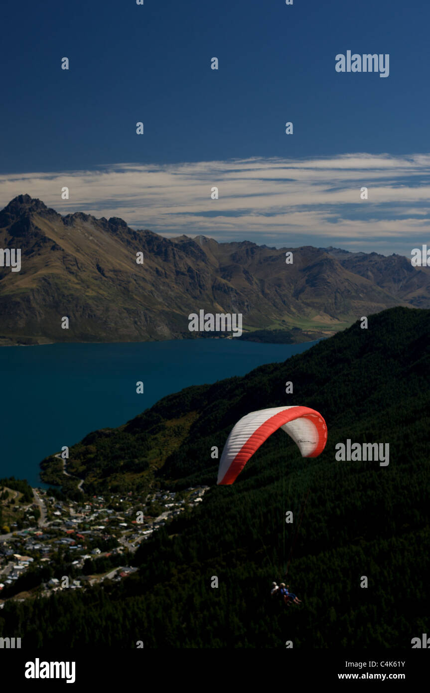 Parapendio volare sopra Queenstown e il lago Wakatipu che mostra il Remarkables gamme della montagna. Foto Stock