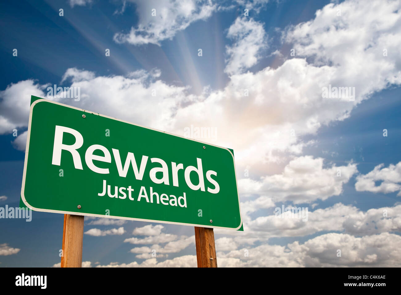 Rewards cartello verde contro le nubi e Sunburst. Foto Stock