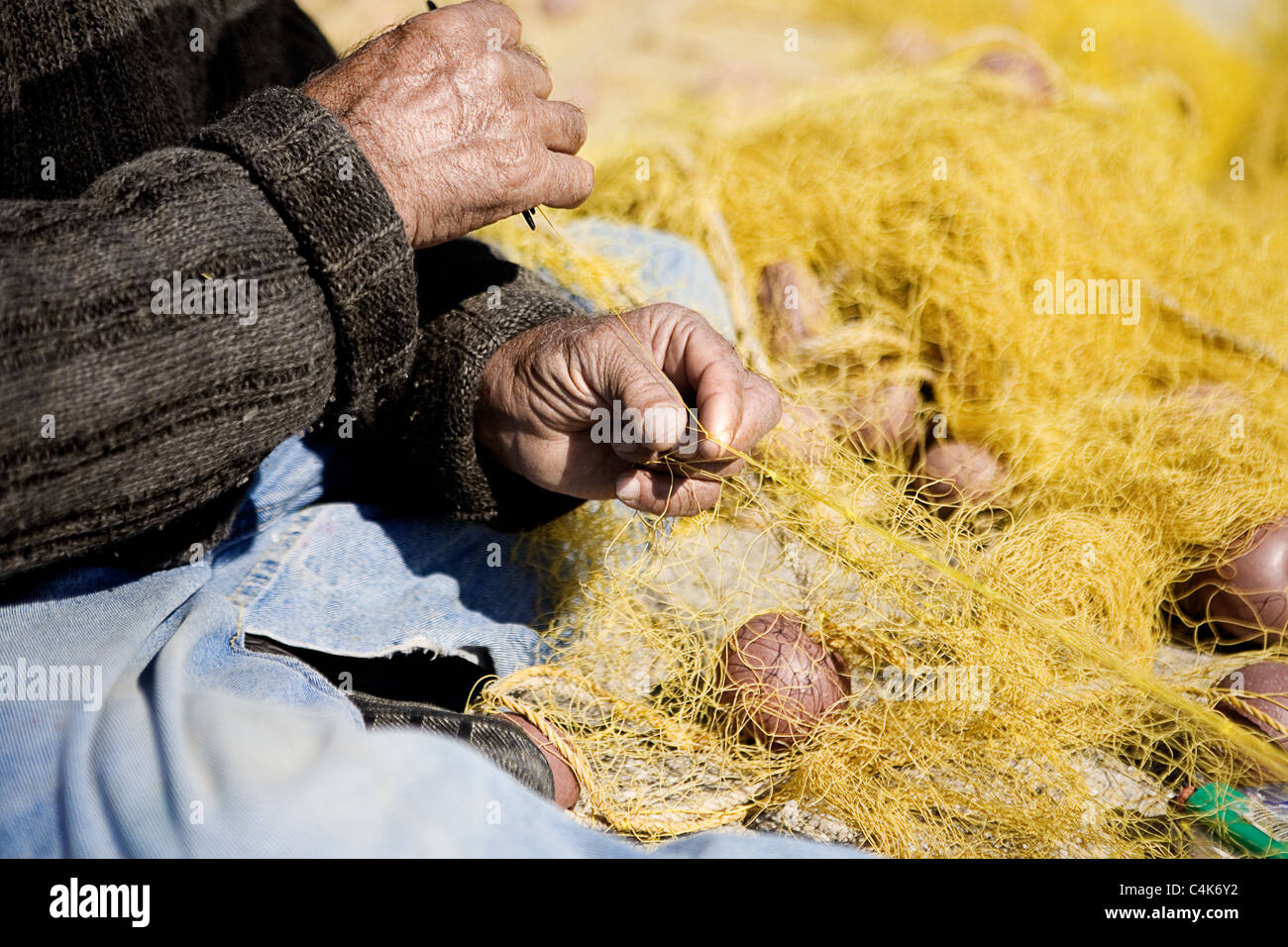 Pescatore greco riparazione di reti da pesca nel porto di Petra - Lesbo Foto Stock