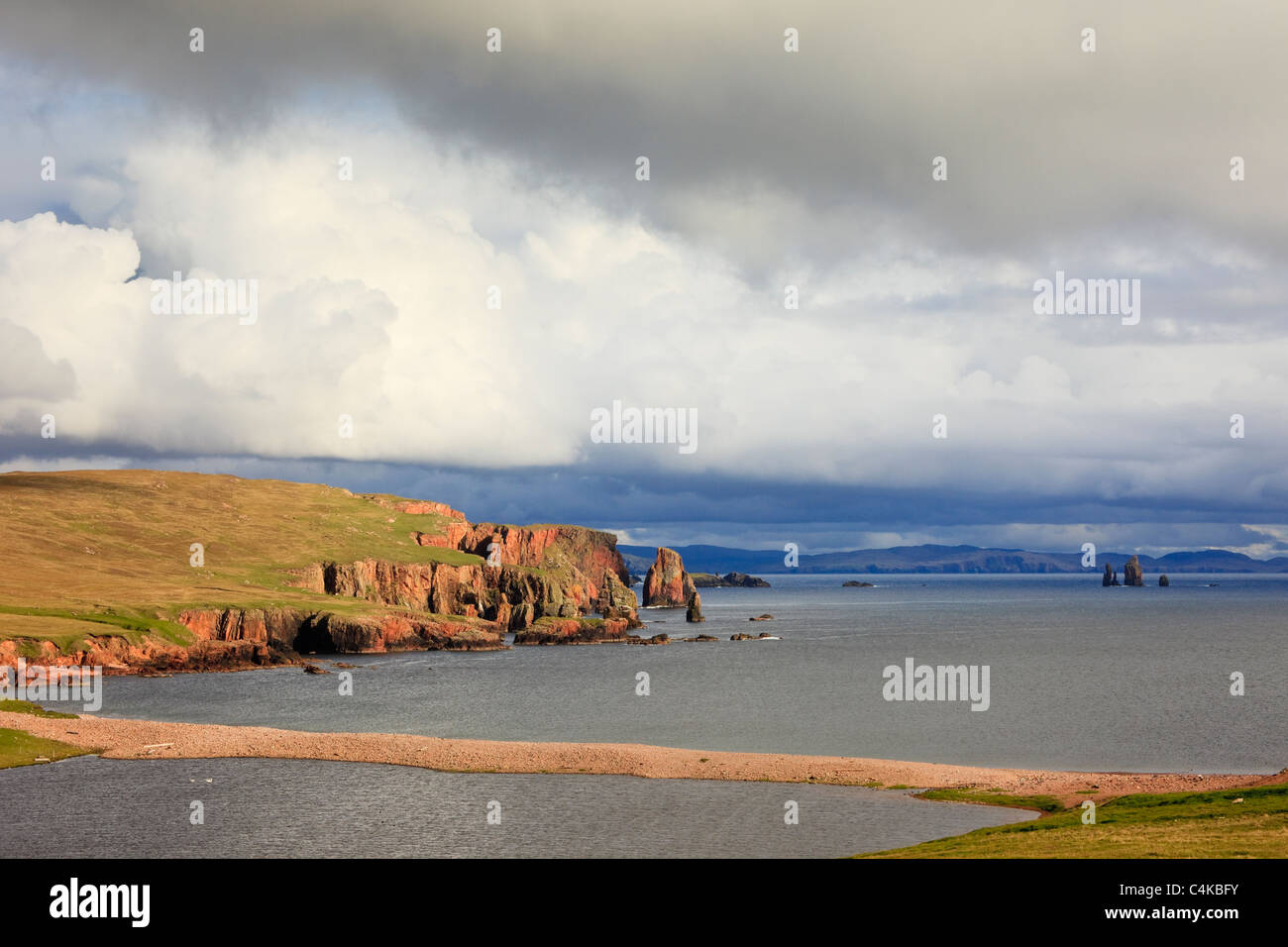 Eshaness, isole Shetland, Scotland, Regno Unito. Vista su tutta la baia Braewick al Neap scogliere e Drongs di arenaria rossa e pile di mare Foto Stock