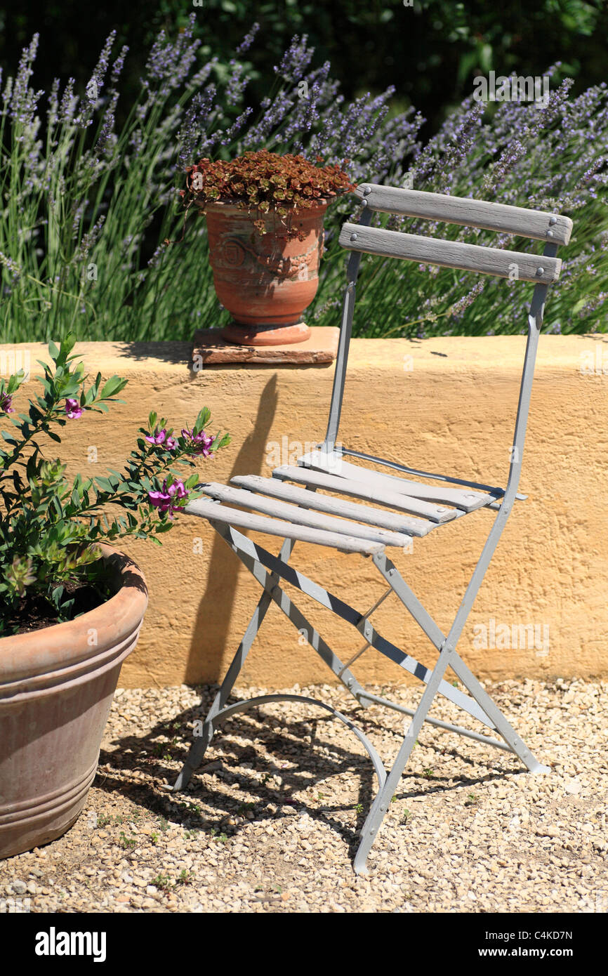 Tradizionale Francese giardino pieghevole in stile caffetteria sedia in giardino interno in Provenza Francia con lavanda e vaso in terracotta Foto Stock