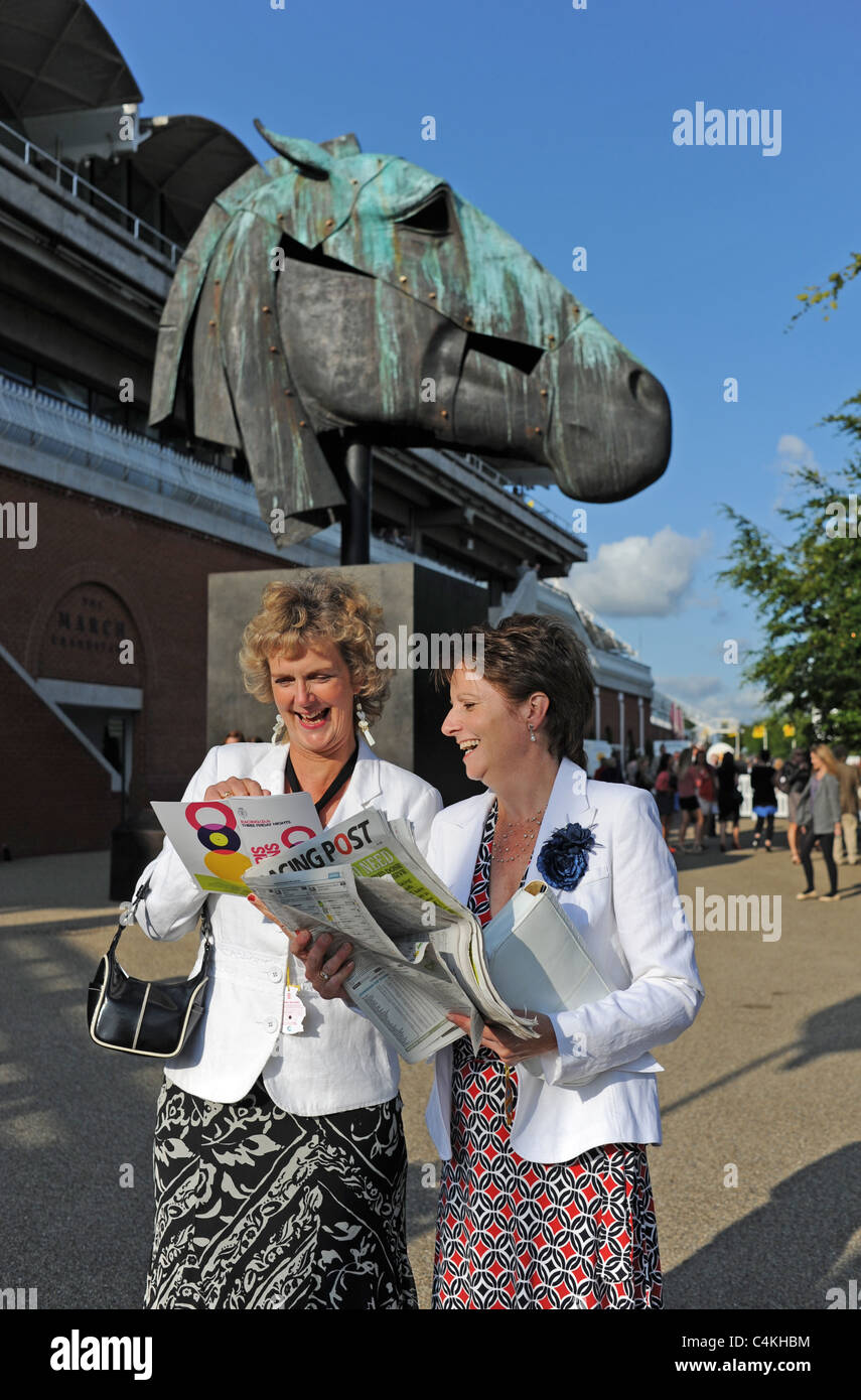 Racegoers femmina a Goodwood riunione serale in giugno la lettura del Racing Post cercando di scegliere un vincitore UK Foto Stock