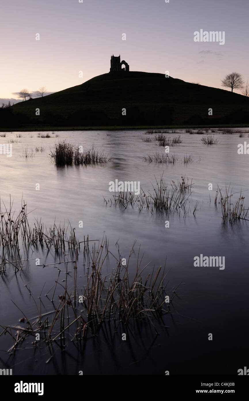 Burrow Mump stagliano contro un pastello tramonto sulla Somerset livelli. Foto Stock