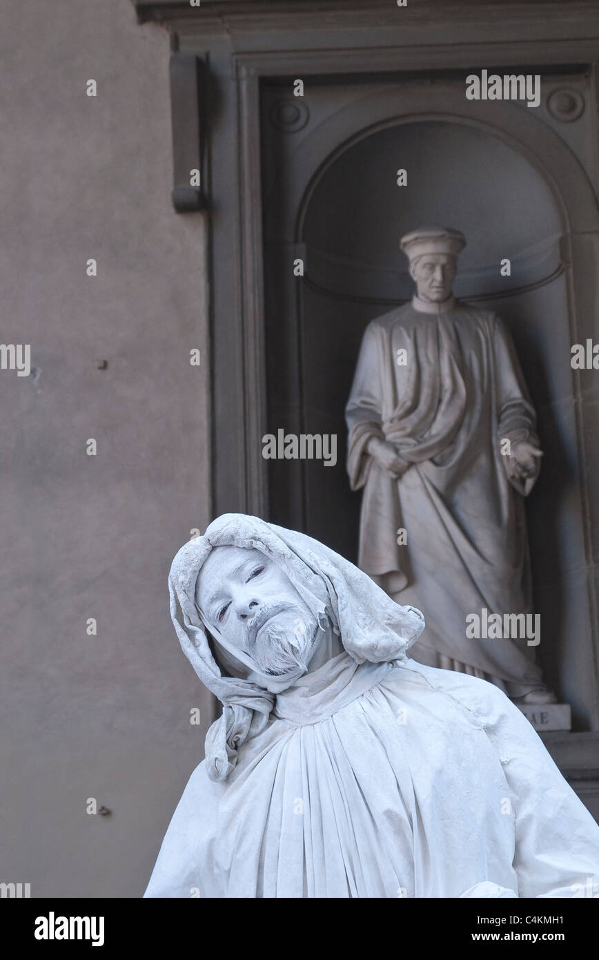 Un mime street performer in piedi di fronte ad una statua di Cosimo Pater Patriae una delle molte statue al di fuori della Galleria degli Uffizi. Foto Stock