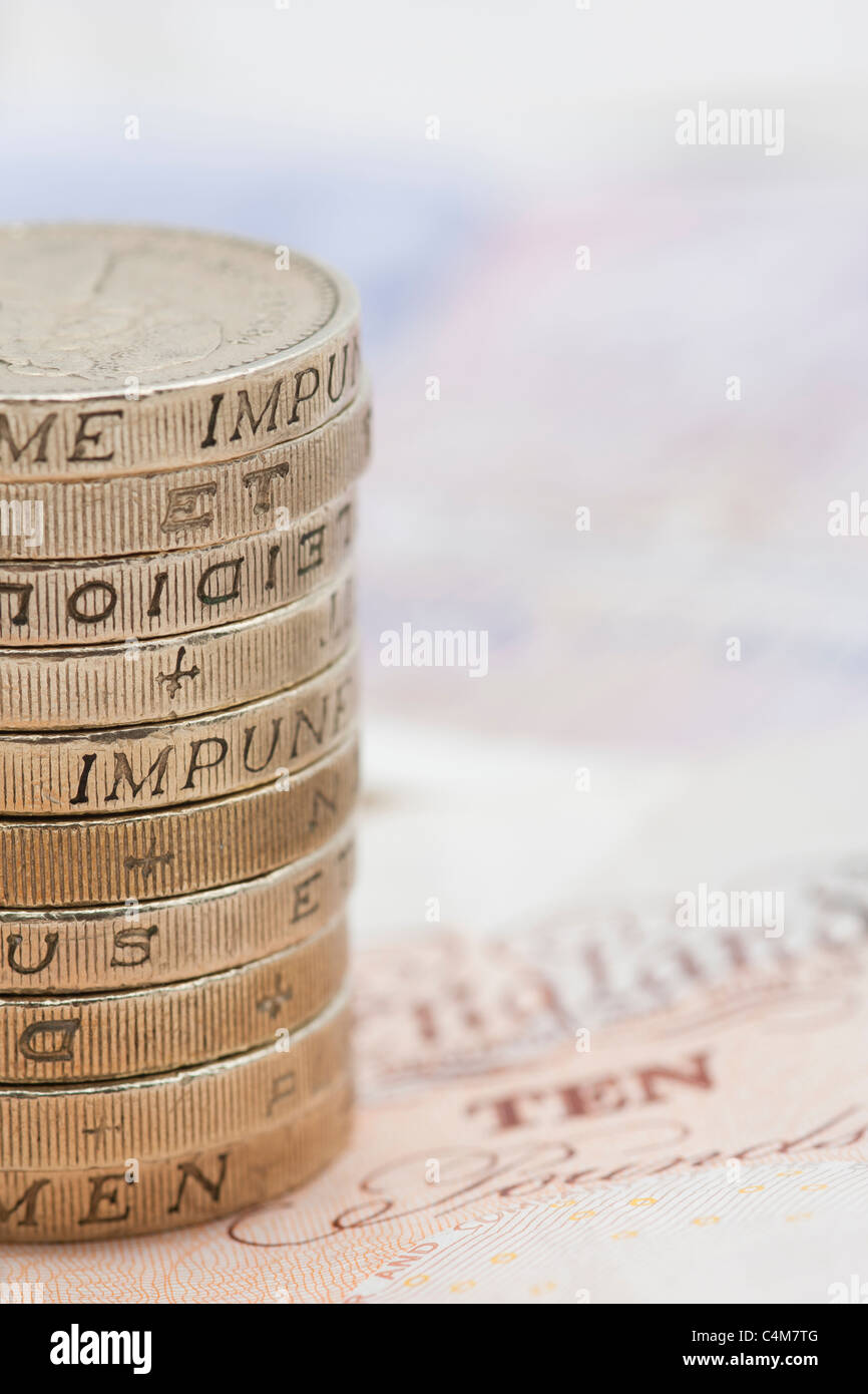 Primo piano della pila / pila di una libbra di monete al di sopra di dieci Pound note Foto Stock