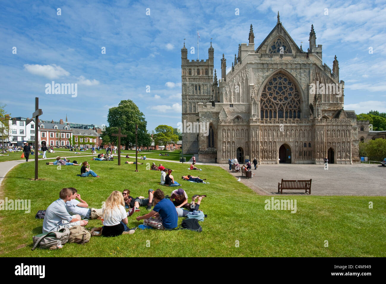 La famosa finestra Occidentale della Cattedrale di Exeter con studenti rilassarsi sul prato della cattedrale verde. Foto Stock