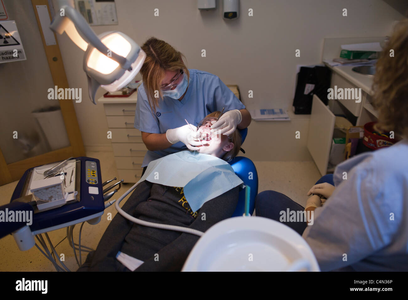 Una ragazza adolescente ottenendo il suo denti esaminati da una donna NHS National Health Service dentista REGNO UNITO Foto Stock