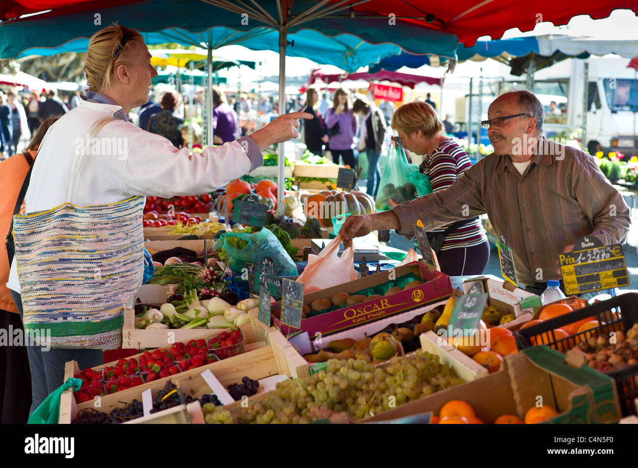 Il francese di servire il cliente al personale di frutta al mercato alimentare a Esplanade des Quais de La Reole, regione di Bordeaux, Francia Foto Stock