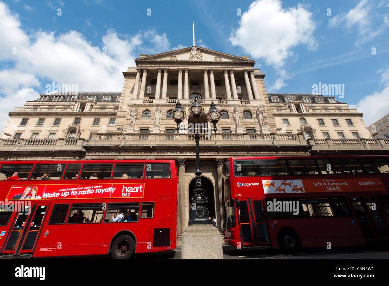 Due autobus rossi passa la banca di Inghilterra edificio in Threadneedle Street, Città di Londra in mattina presto. Foto Stock