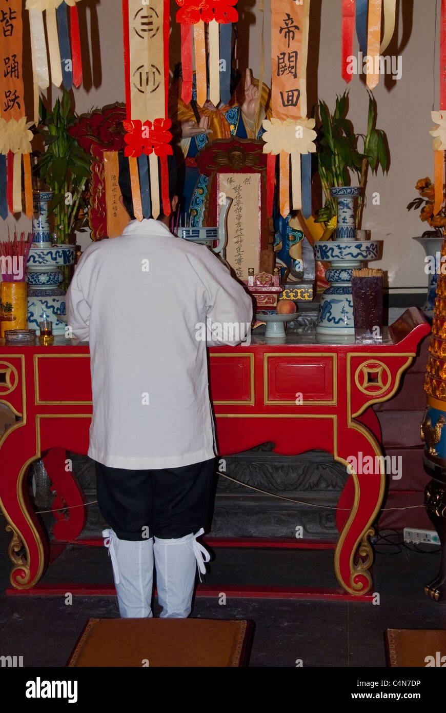 Pechino, Cina, monaco che prega da dietro, all'altare all'interno del Tempio nel 'Financial Street District' diverse culture e religioni Foto Stock