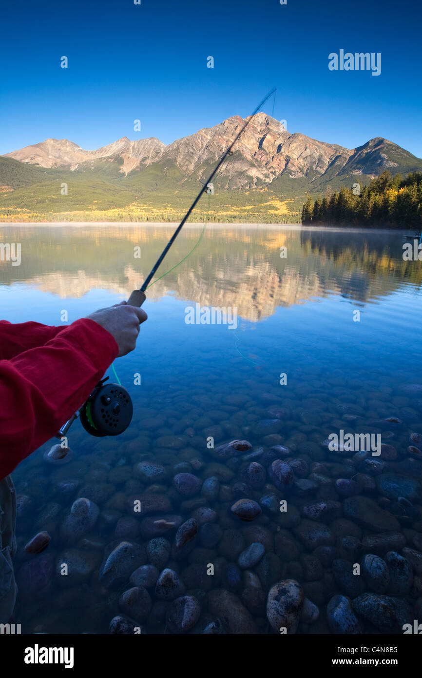 Vicino la mano sulla canna da pesca all'alba, Lago Piramide, il Parco Nazionale di Jasper, Alberta, Canada. Foto Stock