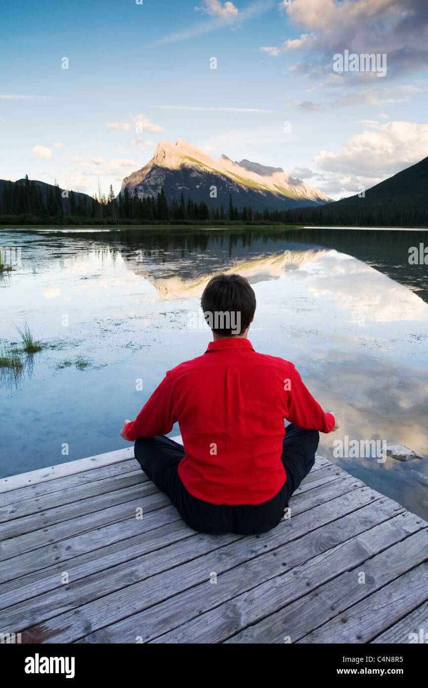 La mezza età uomo meditando sul dock a Vermillion Lake, il Parco Nazionale di Banff, Alberta, Canada. Foto Stock
