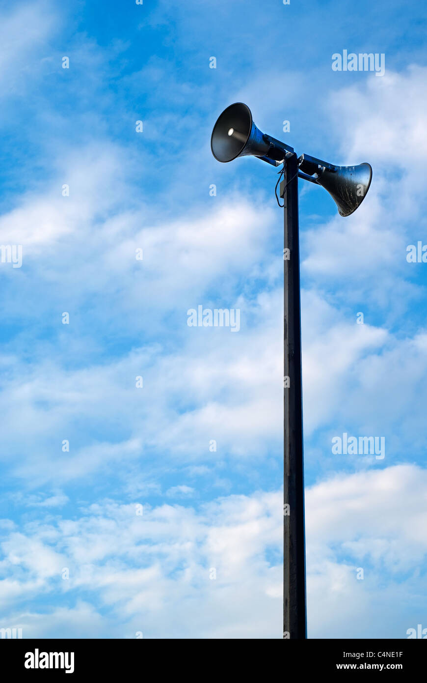 Un sistema di comunicazione al pubblico di altoparlanti torre contro un nuvoloso, blu cielo diurno. Foto Stock
