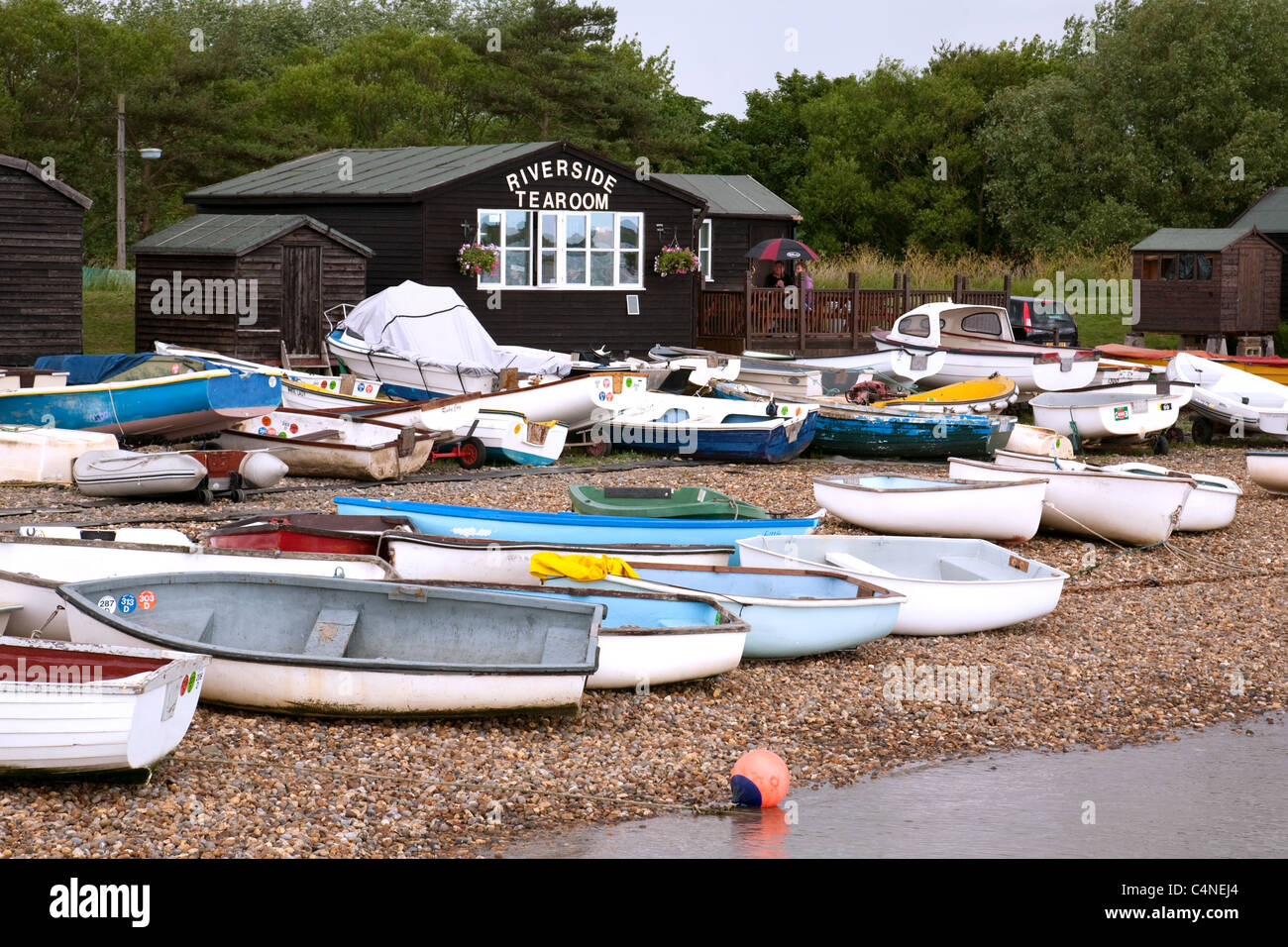 Barche a remi sulla spiaggia presso il porticciolo di Orford, e il Riverside Tearoom, il villaggio di Orford, Suffolk UK Foto Stock