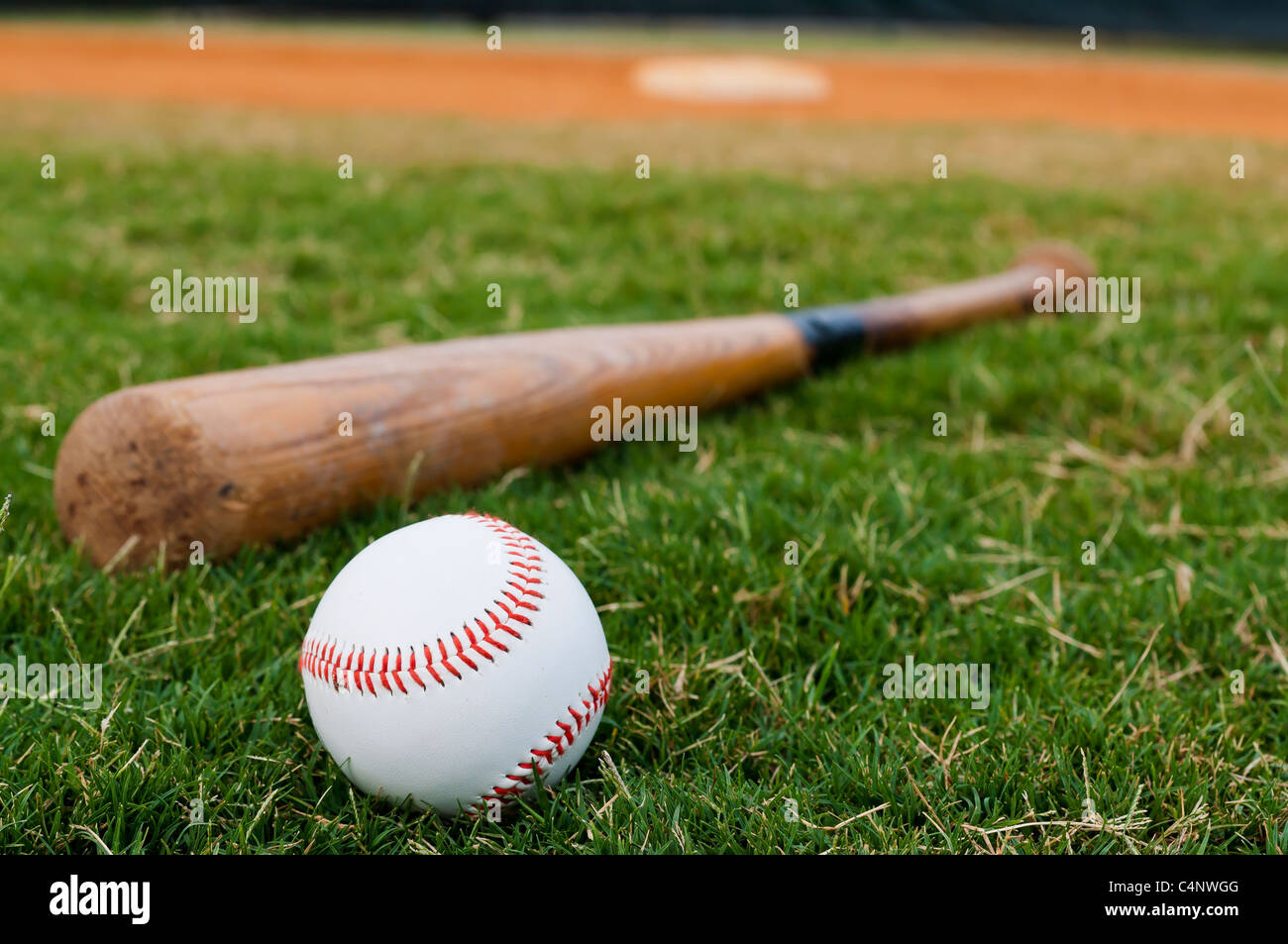 Il baseball e il bat sul campo con base fuori campo lato e in background. Foto Stock