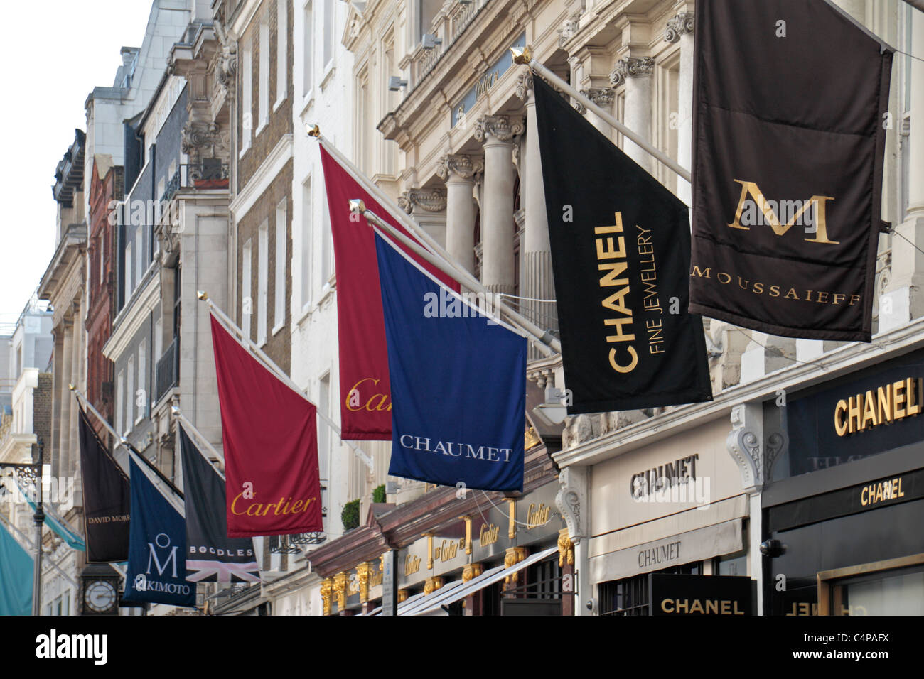 Bandiere che sventolano al di sopra di una linea del designer di lusso negozi di beni su New Bond Street LONDRA, REGNO UNITO. Foto Stock