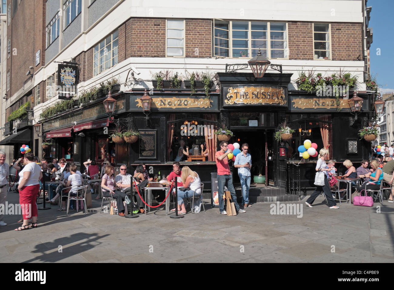 Le persone hanno un drink pomeridiano al di fuori del Sussex public house in St Martins Lane, Covent Garden di Londra, Regno Unito. Foto Stock