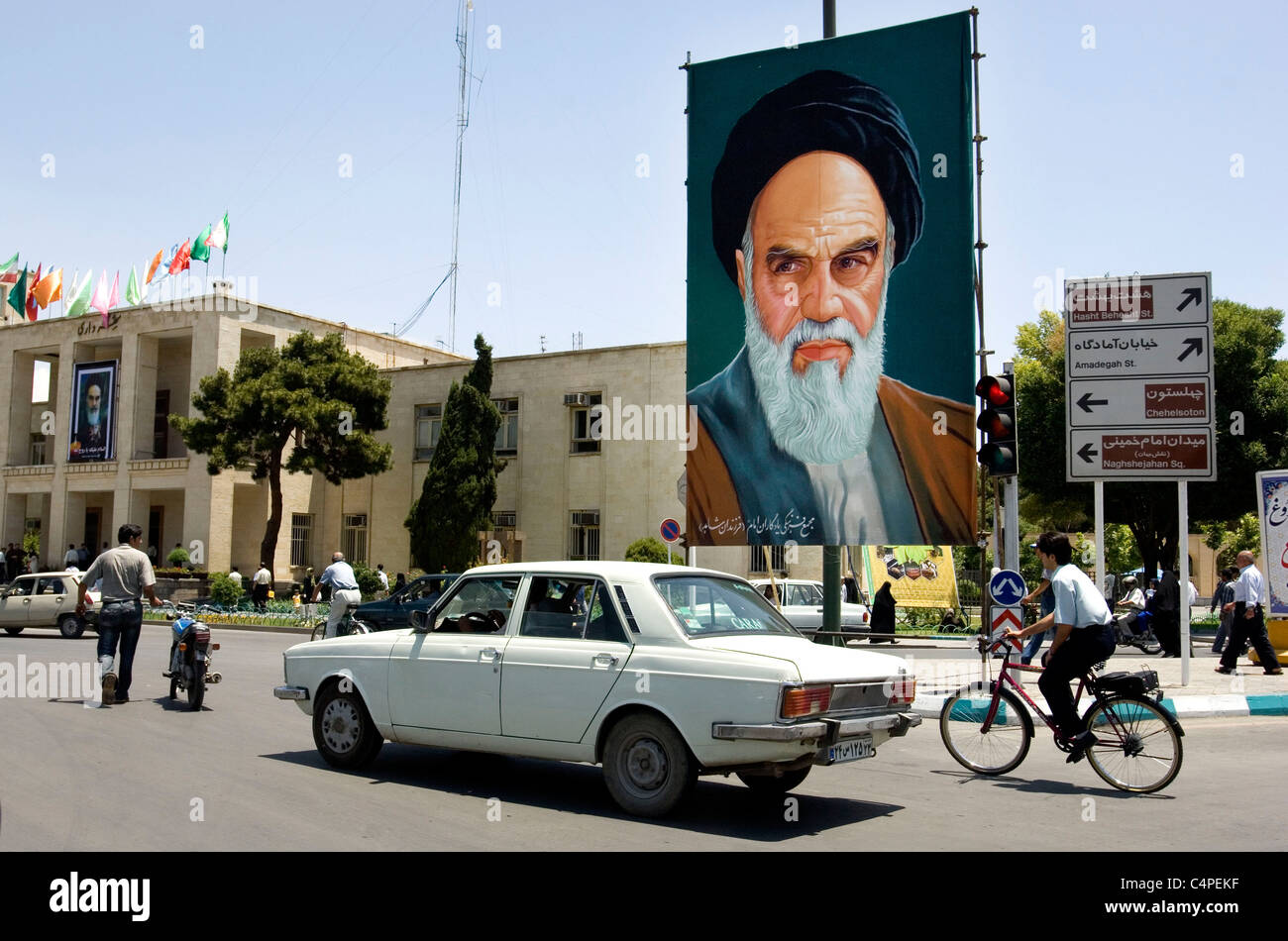 Persone, biciclette ed automobili nel traffico e segno di propaganda con l ayatollah Khomeini, Isfahan, Iran Foto Stock