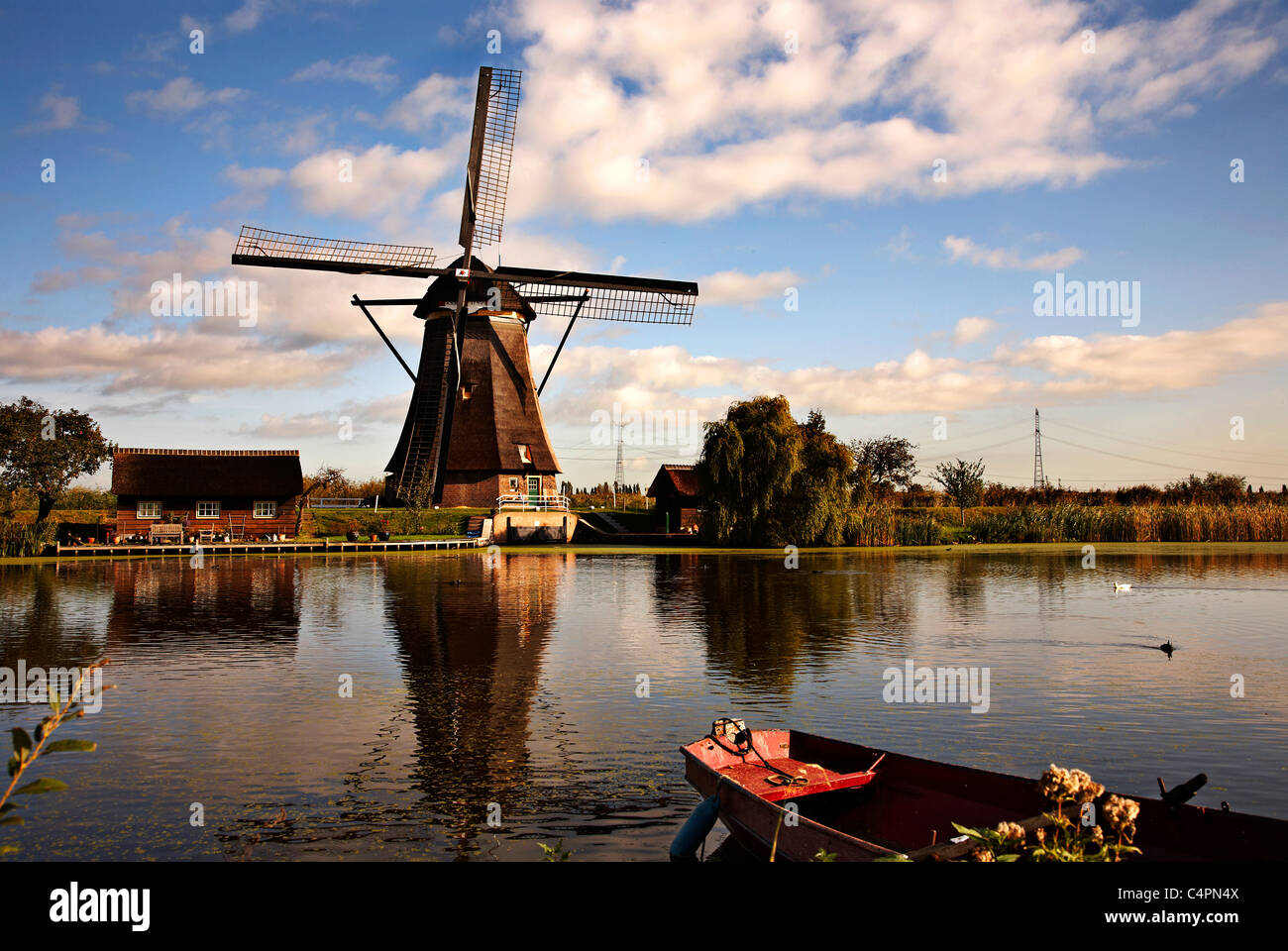 Lo splendido paesaggio della riflessione sul canale di un mulino a vento con una barca in primo piano. Foto Stock