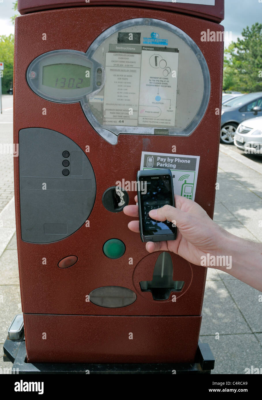 Un pagamento con il Cellulare Parcheggio metro con uomo con cellulare in mano pronti a pagare tasse Foto Stock