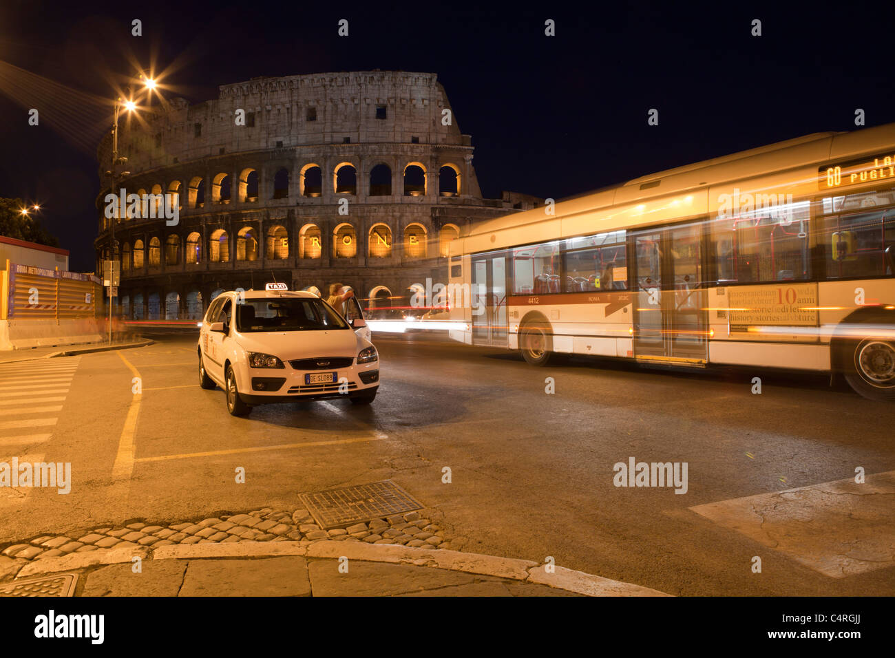 Colosseo Roma di notte con taxi e bus. Foto Stock