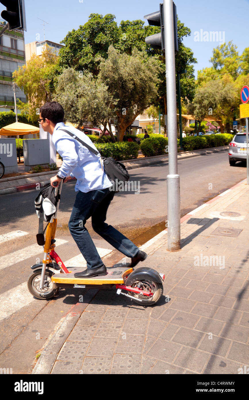 L'uomo della strada di attraversamento con il suo scooter motorizzato di Tel Aviv in Israele Foto Stock