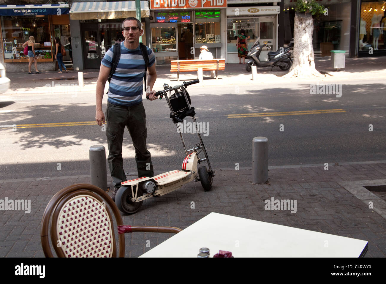 L'uomo con il suo scooter motorizzato su Via Dizengoff Tel Aviv in Israele Foto Stock