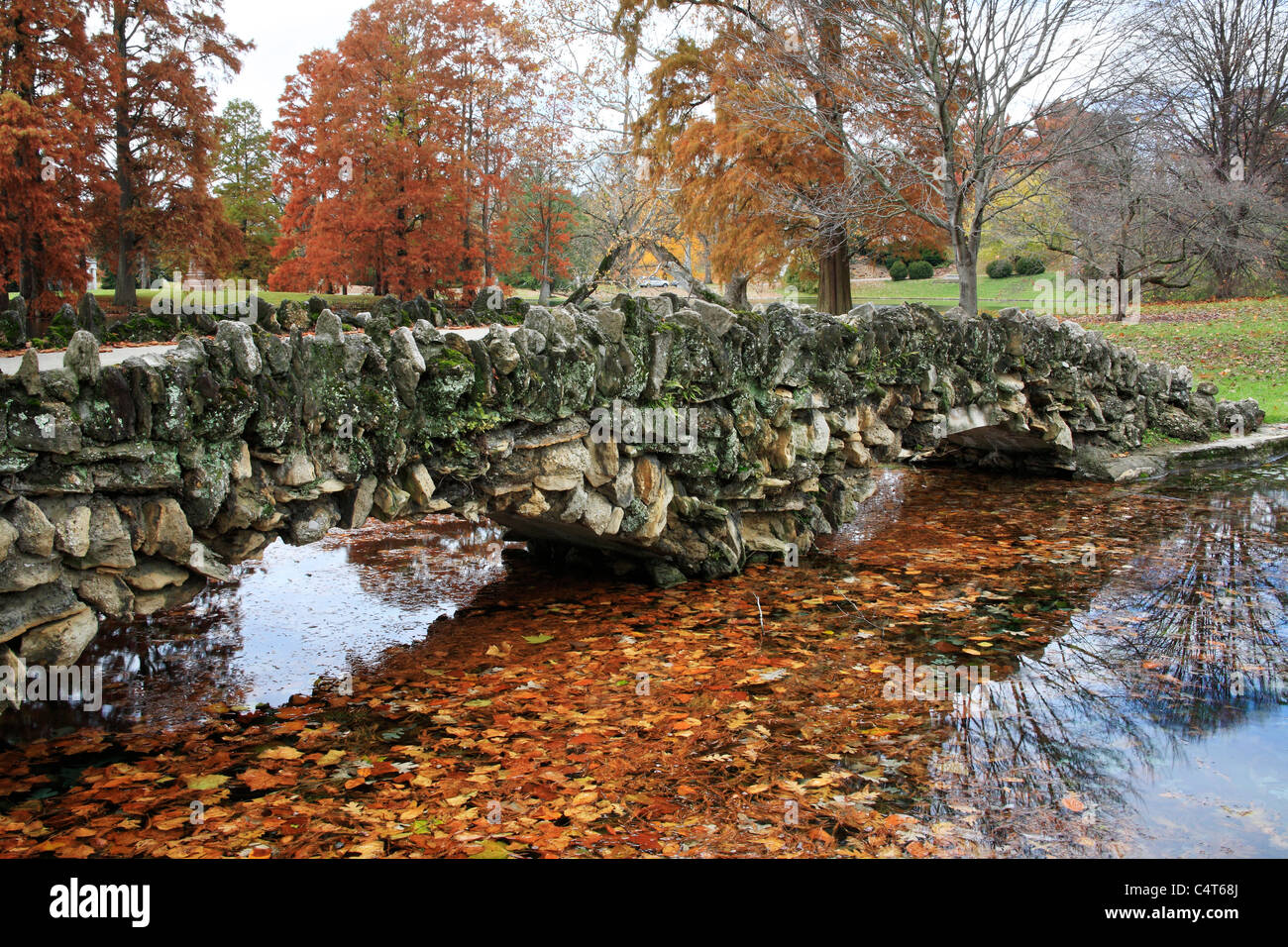 Caduta delle Foglie e un ponte in pietra sopra una tranquilla stagno durante l'Autunno nel parco, Southwestern Ohio, Stati Uniti d'America Foto Stock