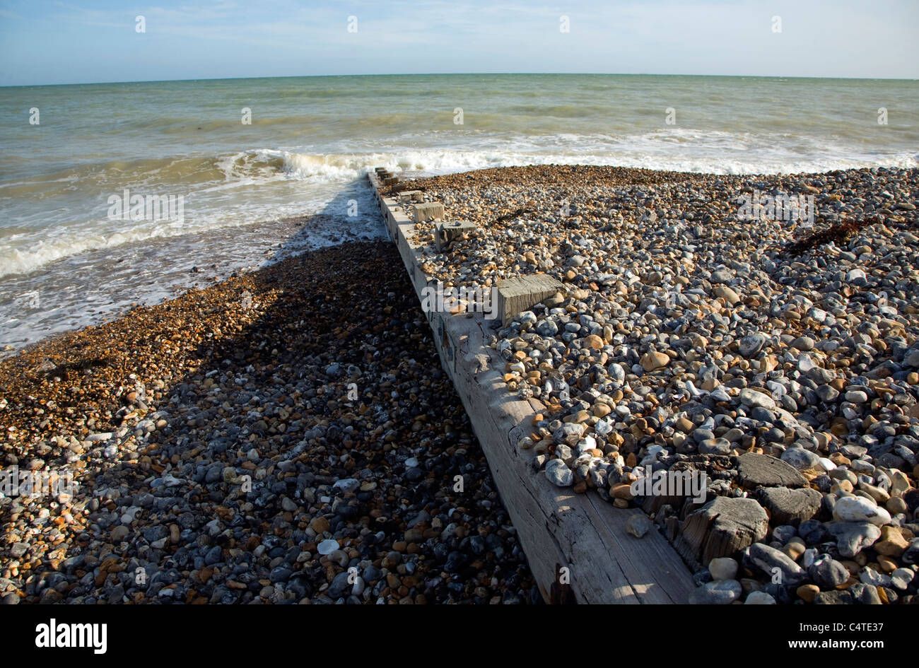 Deriva di Longshore illustrato da sedimenti su entrambi i lati del groyne in legno sulla spiaggia ghiaiosa Foto Stock