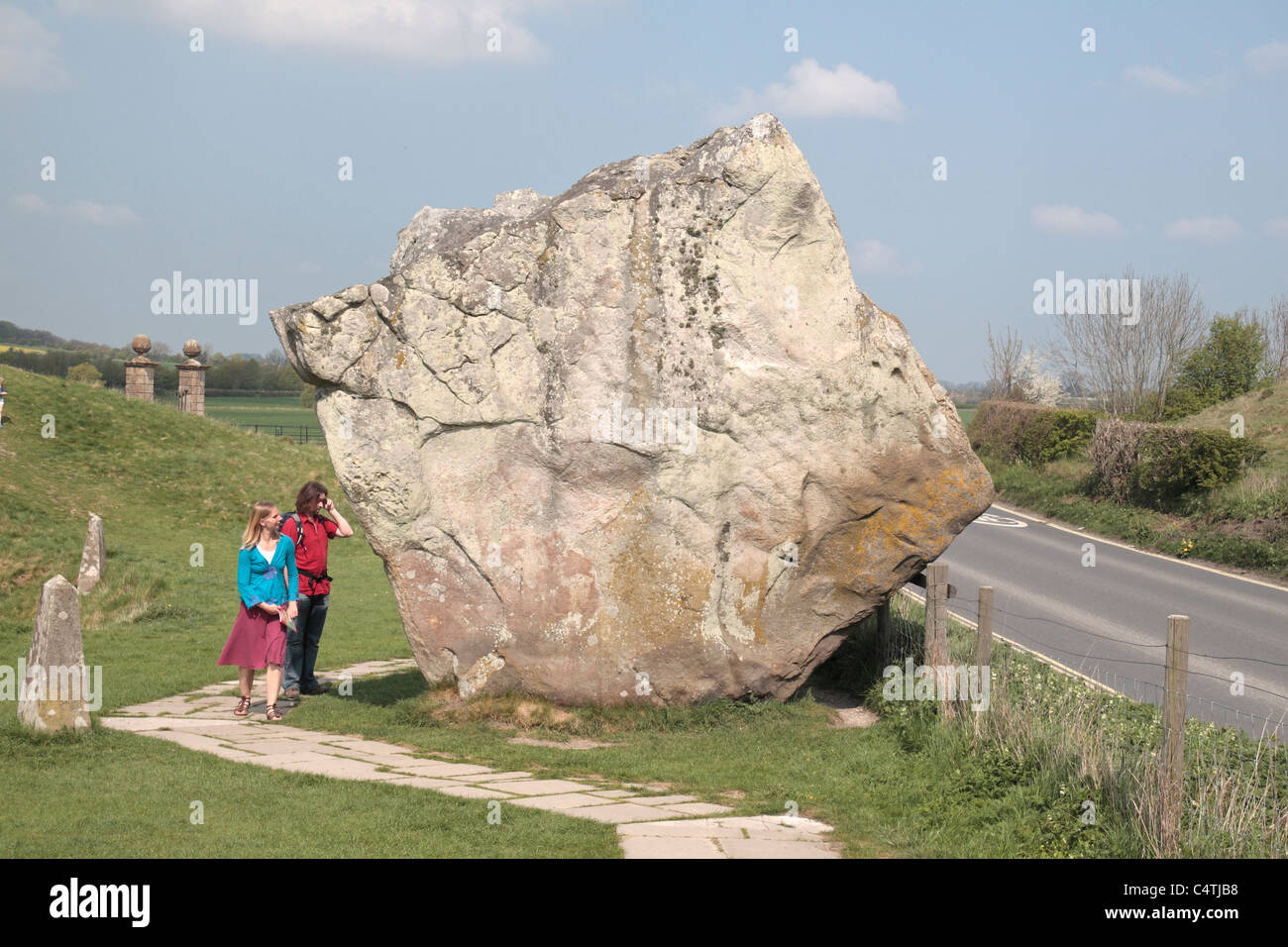 I visitatori a camminare accanto a un enorme cerchio esterno in pietra permanente, Avebury Henge & circoli di pietra sito, Wiltshire, Inghilterra. Foto Stock