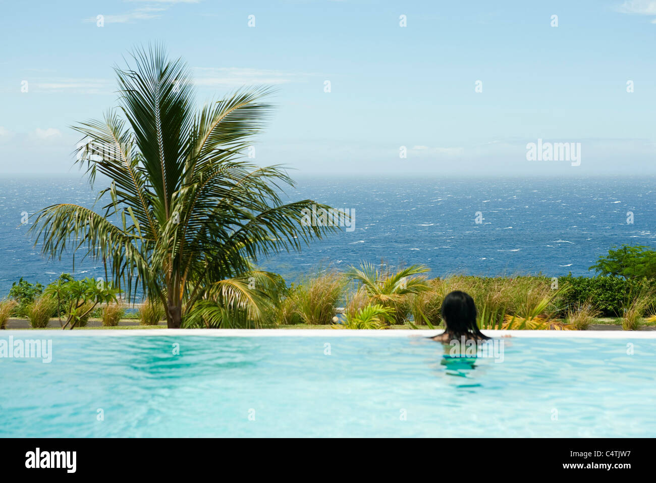 Persona in piscina, guardando il mare Foto Stock