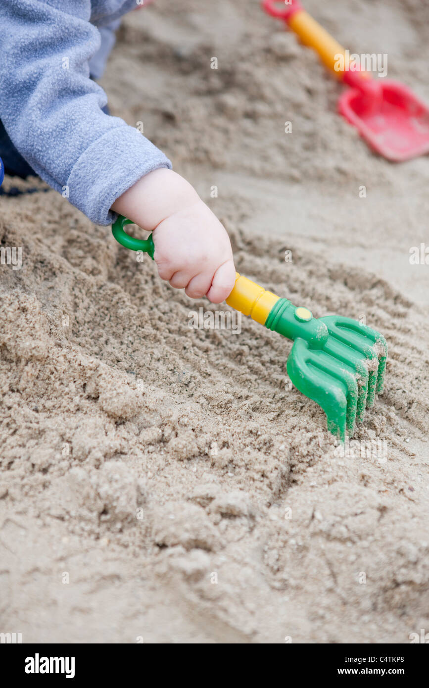 Il Toddler rastrellando sabbia, ritagliato Foto Stock