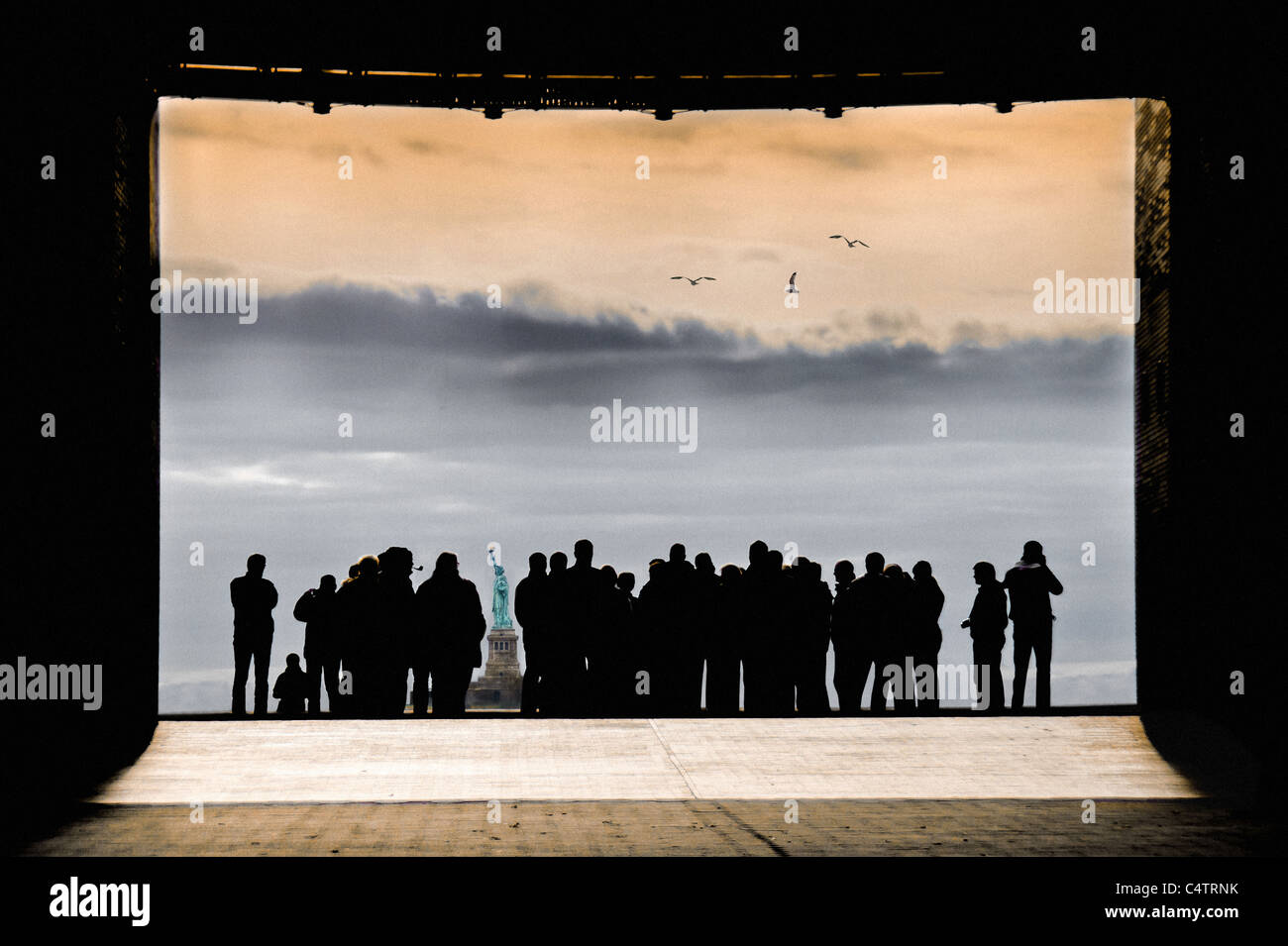 Gruppo folla in silhouette IN PIEDI IN ARCH come cornice guardando la Statua della Libertà Foto Stock