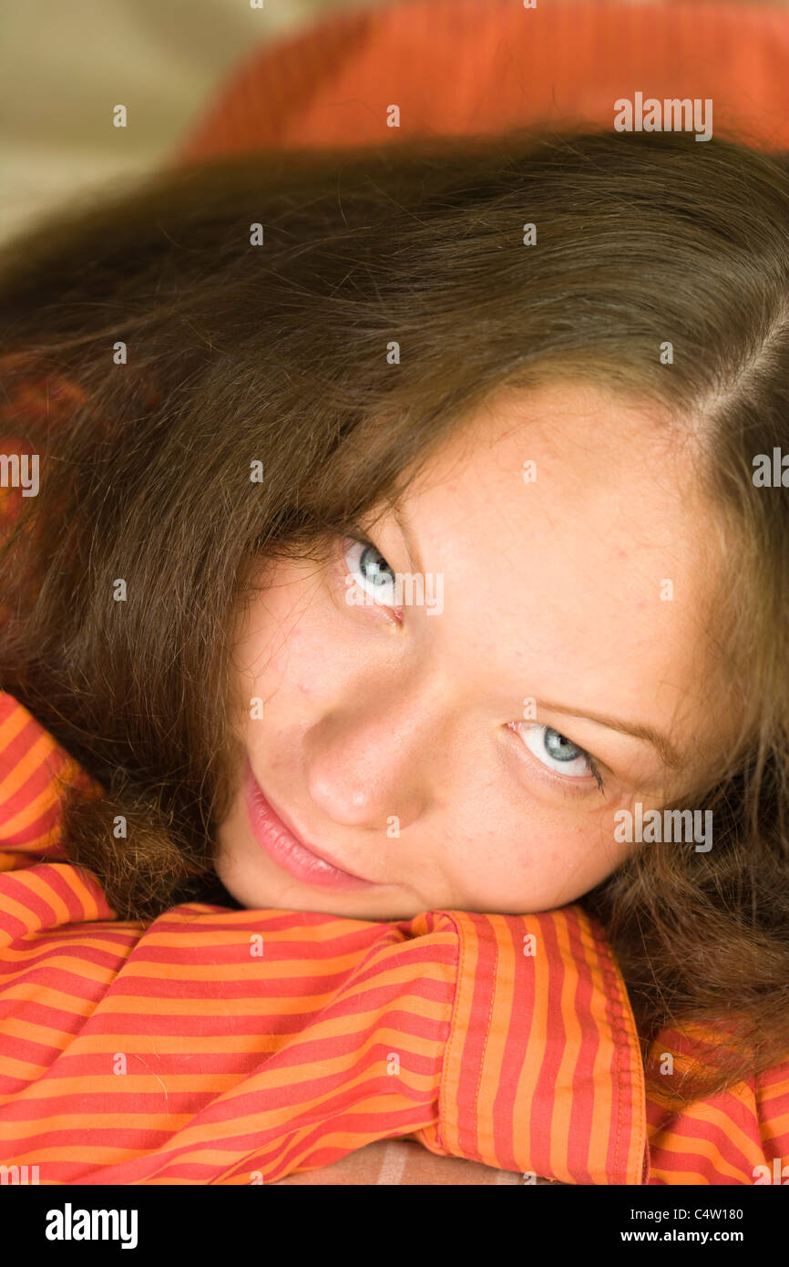 Ritratto di 18 anni ragazza in maglietta arancione giacente sul letto Foto Stock