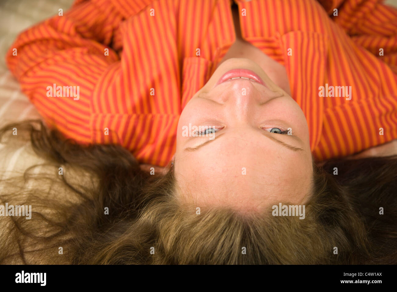 Ritratto di 18 anni ragazza in maglietta arancione giacente sul letto Foto Stock