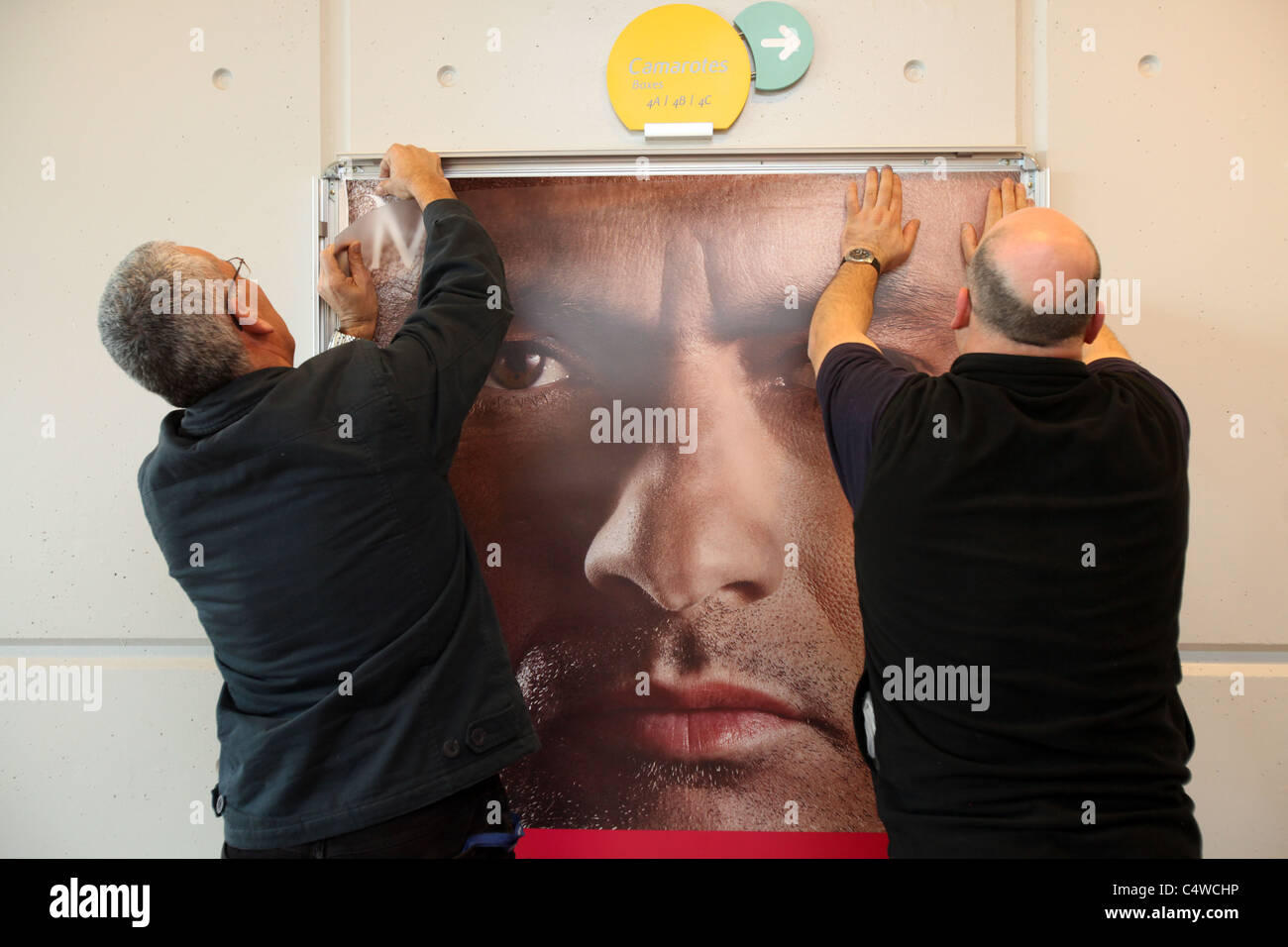 Due uomini mettere poster di un annuncio della banca portoghese Millennium BCP con una chiusura di Jose Mourinho. Foto Stock