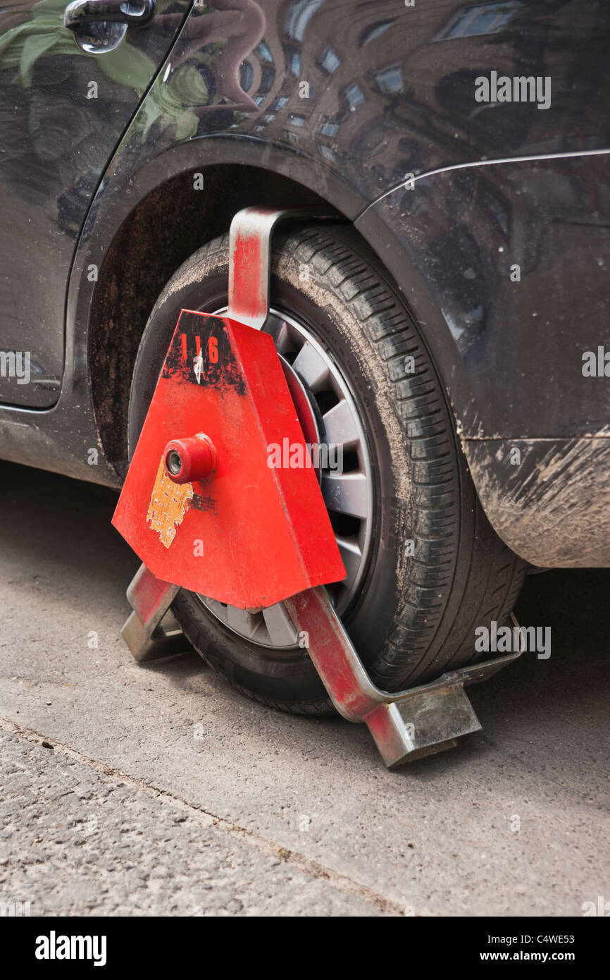 Ein Auto Parkverbot im ist mit einer Parkkralle gesichert | un auto nel parcheggio zona di divieto è fissato con un morsetto di bloccaggio di ruota. Foto Stock
